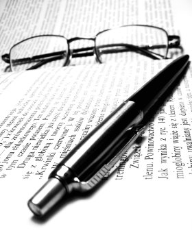 Noticed the text here isn’t English? You’d probably make a good proofreader! Spectacles and a pen lying on a book